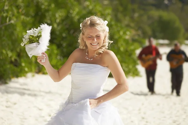 Gorgerous bride walking to wedding ceremony on the beach with bo