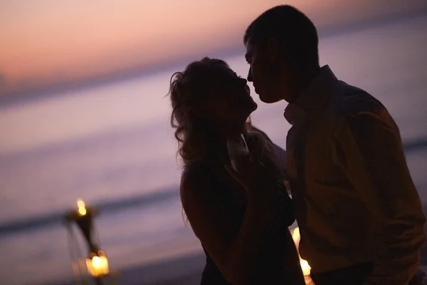 Beautiful young couple kissing on twilight, standing near table.