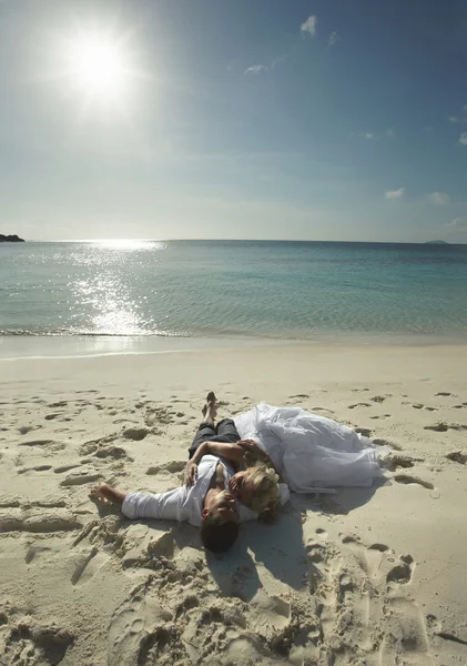 Beautiful young couple kissing on sunset lying on sand, sunset t