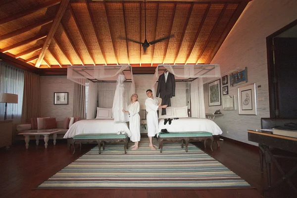 Nice couple preparing to wedding in bedroom with canopy bed.