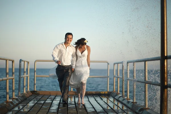 Gorgeous wedding couple running through the spray, splashes and