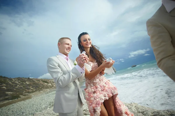 Attractive wedding couple letting go white doves at beautiful ce