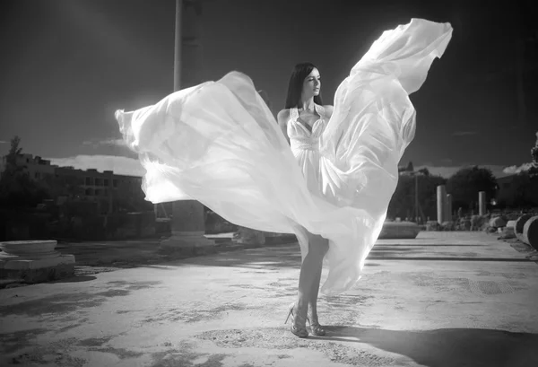 Ethereal, divine bride with flying, shiny dress standing in temp