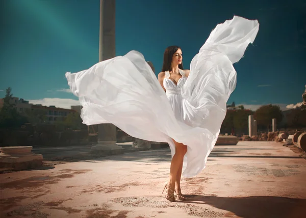 Ethereal, divine bride with flying, shiny dress standing in temp
