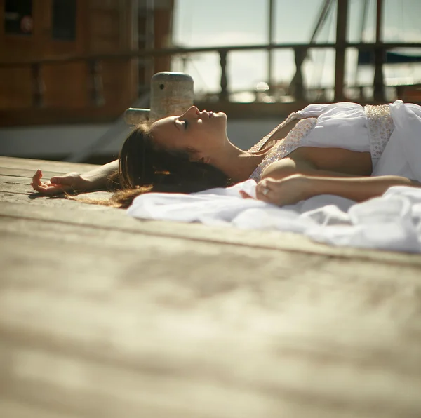Beautiful, glamorous woman, girl lying on wooden pier in yacht c