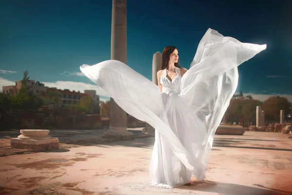 Ethereal, divine bride with flying, shiny dress standing in temp