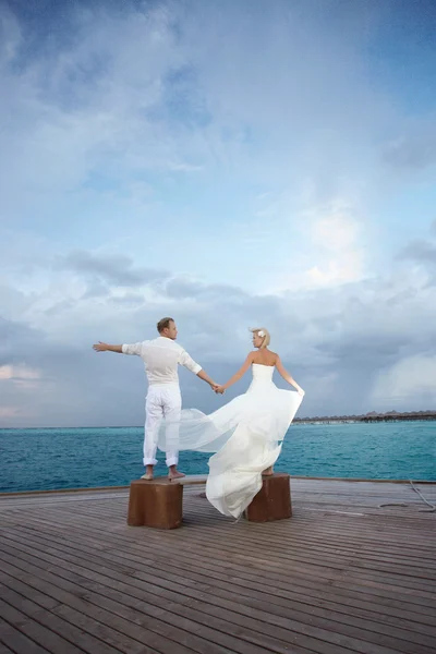 Gorgerous just married couple standing on pier after wedding.