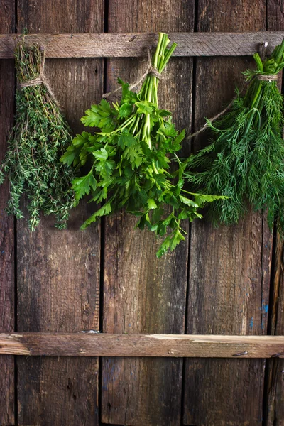 Bunch of thyme, dill and parsley hanging  on old wooden board