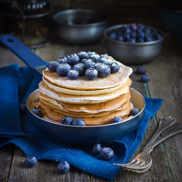 Pancakes with blueberry and powdered sugar in pan