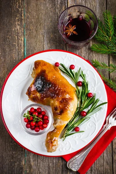 Roasted chicken leg served with rosemary and cranberry on white