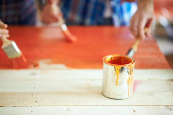 Can of orange paint with a paint brush