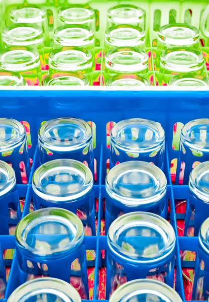 Empty water glasses arranged in blue and green  plastic box