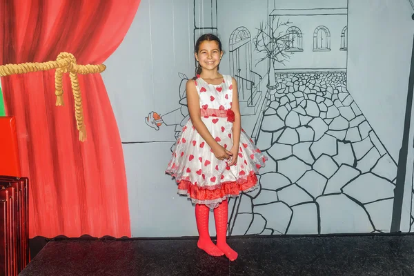 Nine year old girl posing in a playroom in a pretty dress