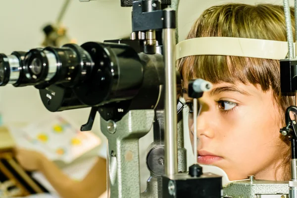 Little girl taking the eye exam test at optometrist office
