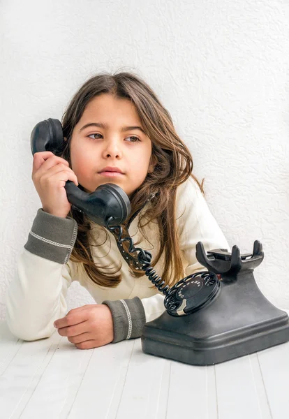 Seven year old girl with old vintage phone before white backgrou