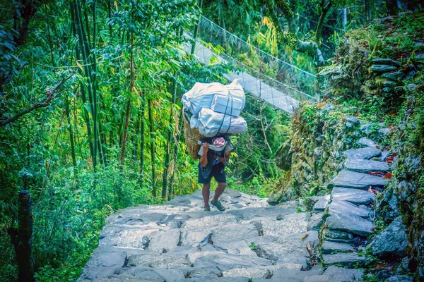 Men in Nepal is carrying a big heavy load on his back