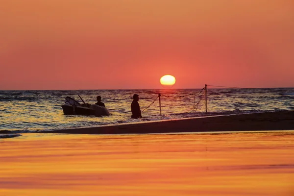 Golden sunset over the sea with the boat silhouette and fisherma