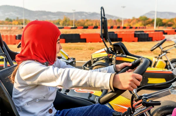 Little girl is driving Go- Kart car in a playground racing track