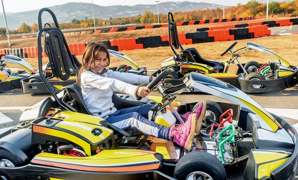 Little girl is driving Go- Kart car in a playground racing track