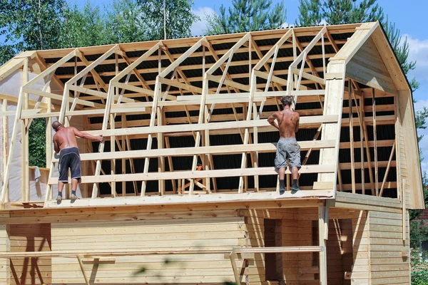 Two workers erecting roof frame.