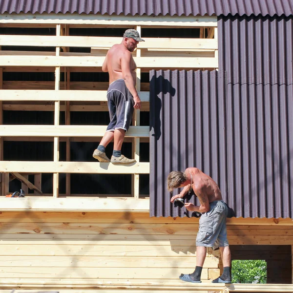 Two workers are fixed parts of a soft roof.