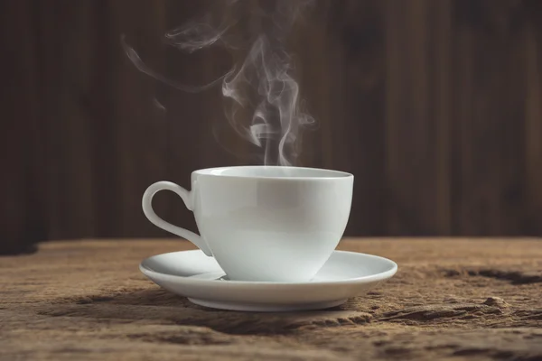 White coffee cup with smoke on wooden table