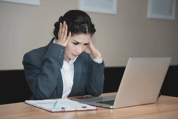 Businesswoman working on laptop with headache having stress in the office