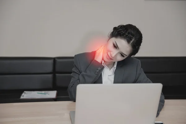 Businesswoman working on laptop with neck pain