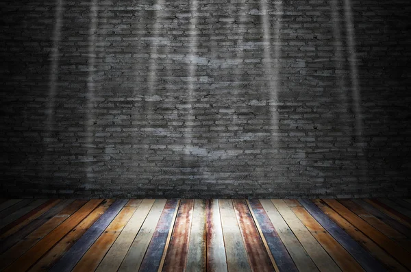 Light in dark room with colorful wooden floor and grunge stone w