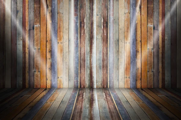 Light in dark room with colorful wooden floor and grunge stone w