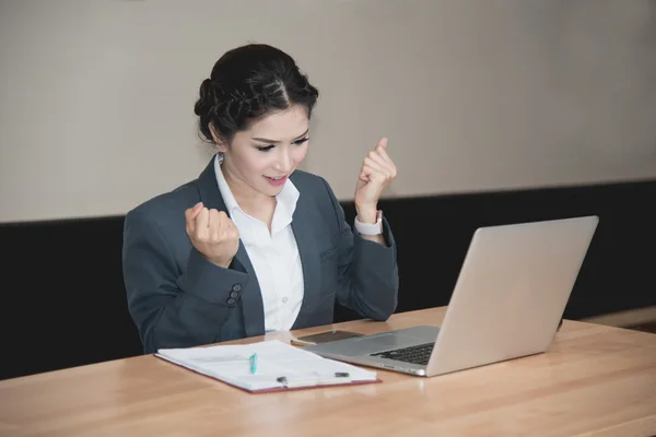 Business woman happy when work success with laptop on wooden tab