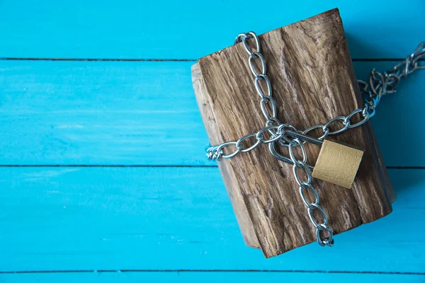 Locked wooden treasure box on blue wood background
