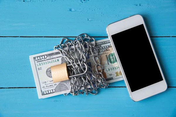 Phone and locked dollar money by metal chain link with padlock