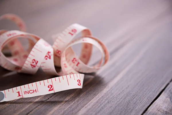 White measuring tape on wood background