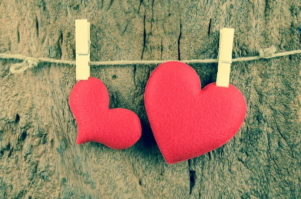 Lovely red hearts hanging on the clothesline on old wood backgro