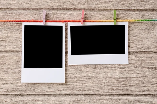 Empty black photo frames hanging with clothespins on wooden back