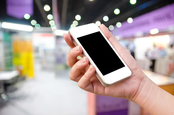 Woman hand holding the phone tablet on blur event background