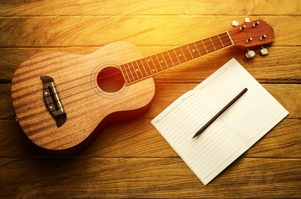 Ukulele guitar with blank notebook and pencil