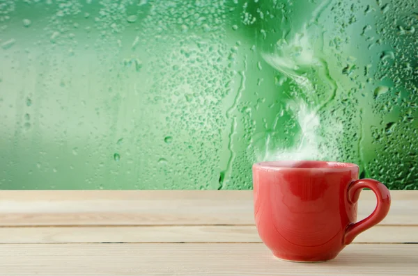 Coffee cup with natural water drops on glass window background