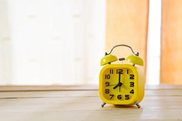 Yellow alarm clock on wood table