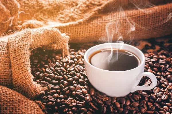 White coffee cup with smoke and coffee beans around