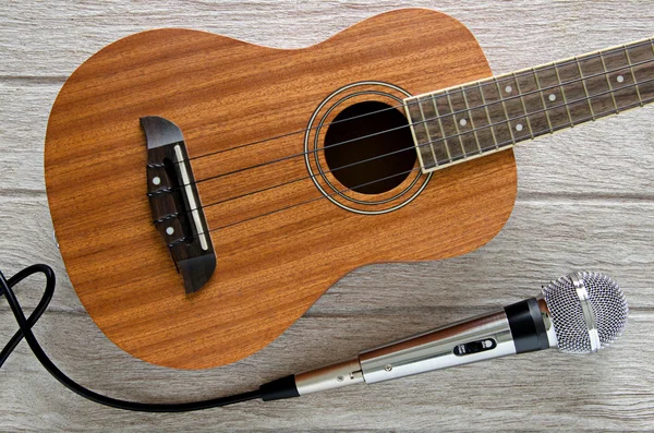 Microphone and ukulele guitar on white wooden table