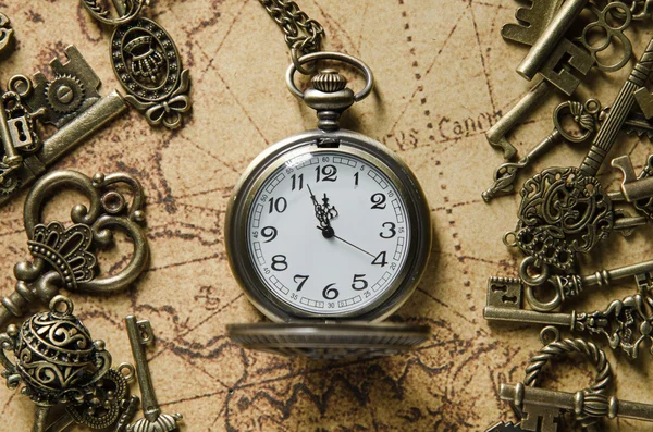 Vintage pocket watch and skeleton key on ancient map background