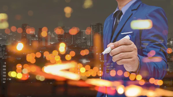 Business man use pen write with city bokeh blurred background