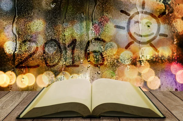 Open book with water drop glass sunsign and year 2016