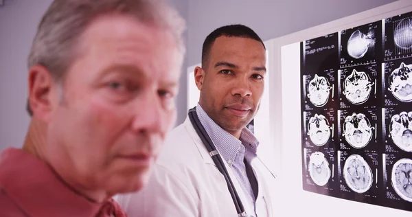 Young intelligent doctor looking at camera with mid aged patient