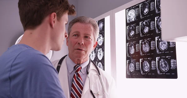 Young male adult caucasian reviewing brain xrays with mid aged p
