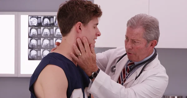 Portrait of mid-aged doctor check sports athlete neck injury