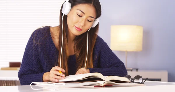 Asian woman listening to music while doing homework