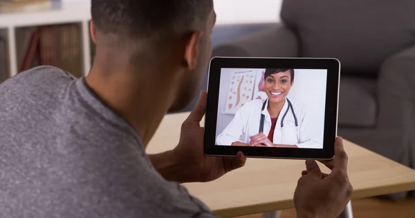 Black man talking to doctor on tablet